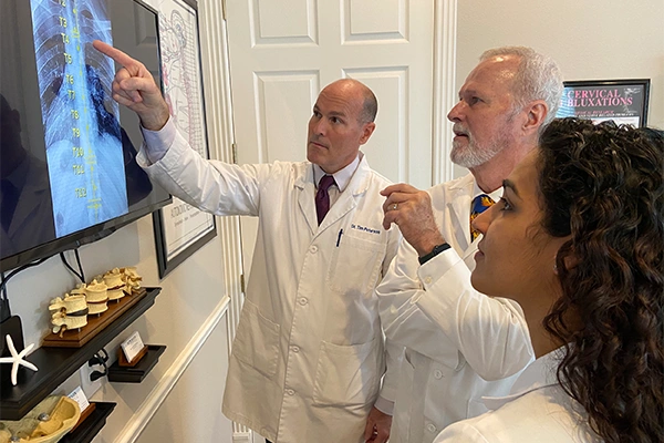 Chiropractor Tim Peterson and Ward Peterson pointing to an x-ray