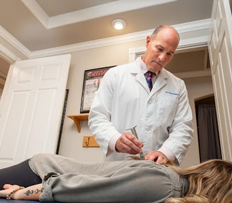 Doctor using a device on a patient during an examination while they lay face down on an exam table